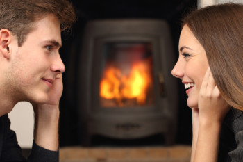 Side view of a couple flirting and looking each other in front a fireplace